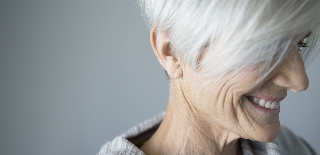 Close up portrait smiling senior woman looking down